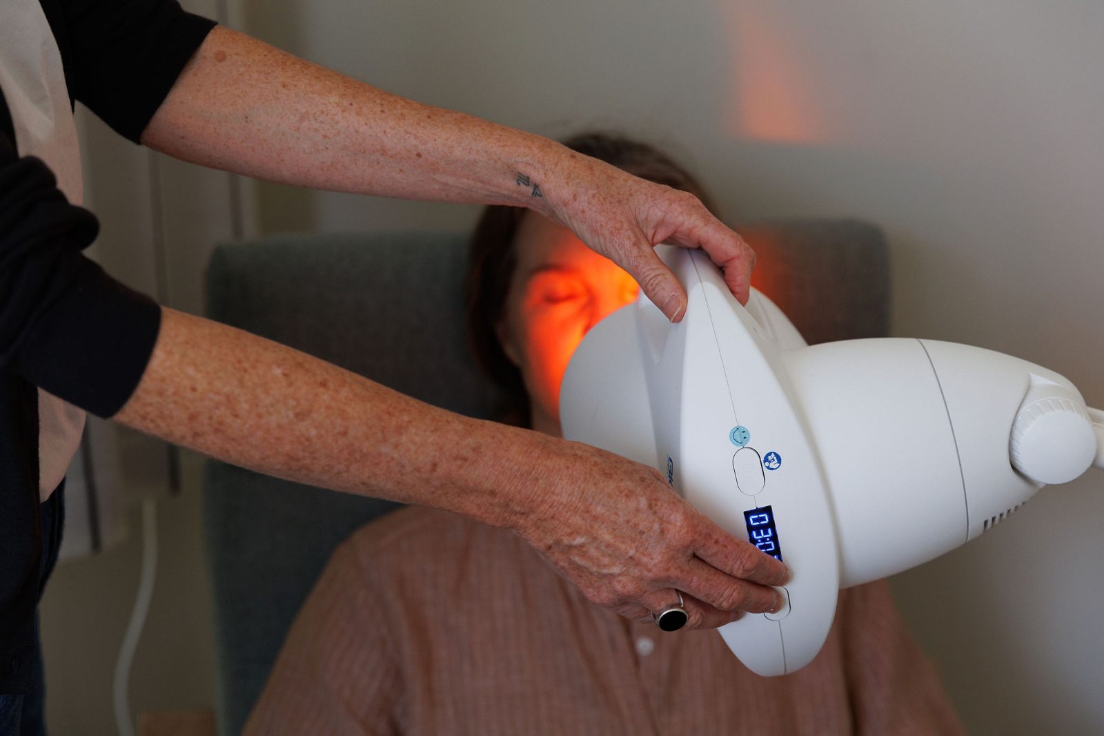 Caroline's hands positioning the Bioptron light for a client