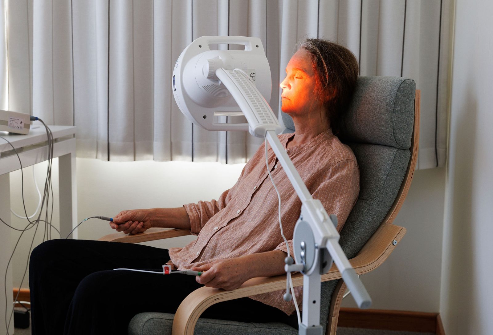 A client reclining with her eyes closed as warm Bioptron light falls on her face