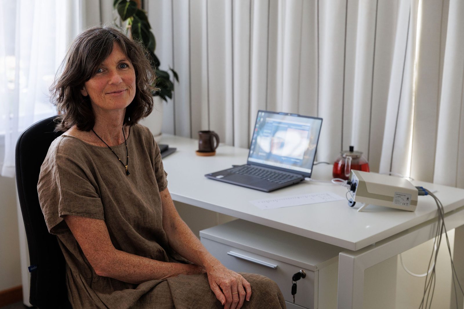 Caroline seated at her desk in the home studio, beside the ATM Express system