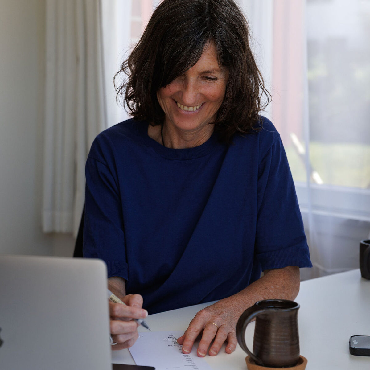 Caroline smiling as she writes notes at her desk in the home studio